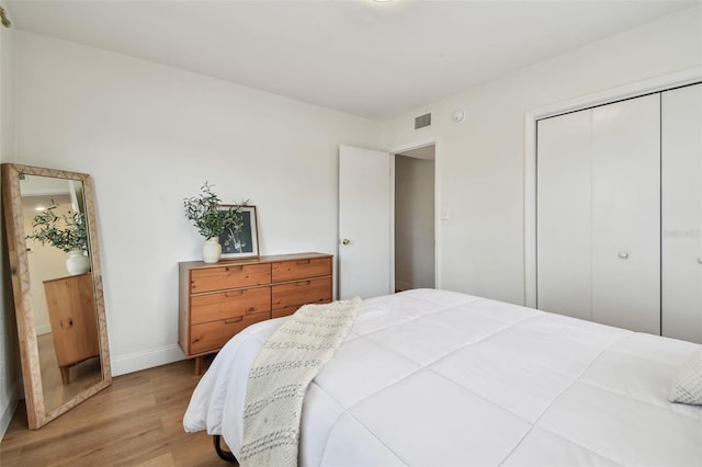 bedroom with light wood-style floors, baseboards, and a closet