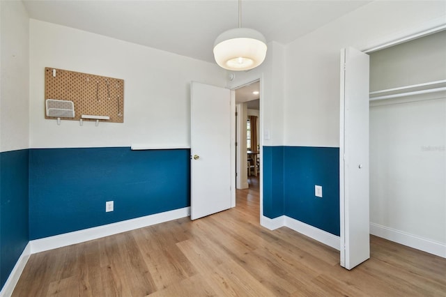unfurnished bedroom with wood finished floors, baseboards, and a closet