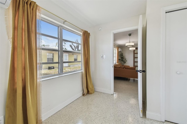 hallway with speckle patterned floor and baseboards