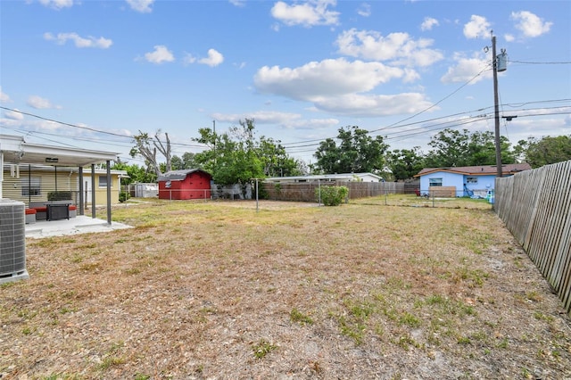 view of yard featuring a patio area, central AC, a storage shed, and an outbuilding