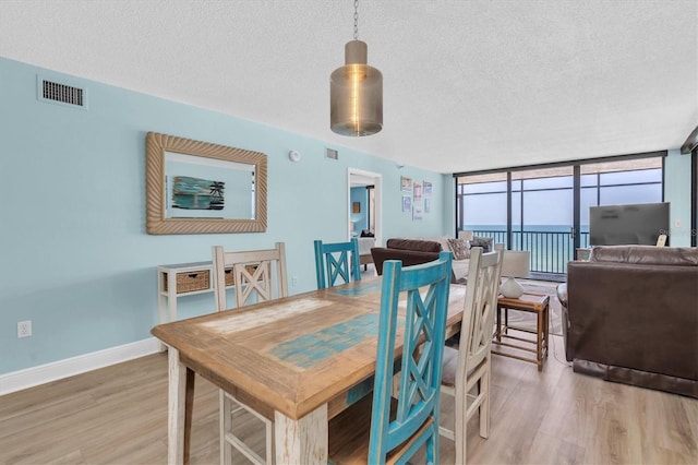 15400 Gulf Blvd Unit 202, Madeira Beach, FL 33708 - dining room with a textured ceiling, light wood-style flooring, baseboards, visible vents, and expansive windows