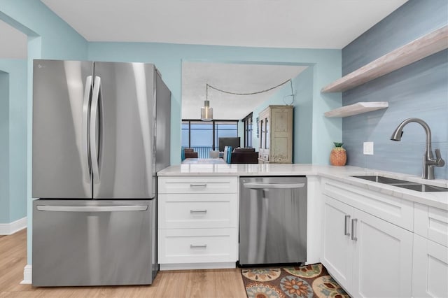 15400 Gulf Blvd Unit 202, Madeira Beach, FL 33708 - kitchen with open shelves, white cabinetry, a sink, light wood finished floors, and appliances with stainless steel finishes