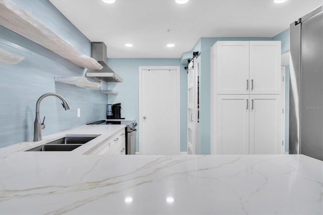 15400 Gulf Blvd Unit 202, Madeira Beach, FL 33708 - kitchen with light stone countertops, stainless steel range with electric stovetop, a sink, white cabinets, and wall chimney exhaust hood