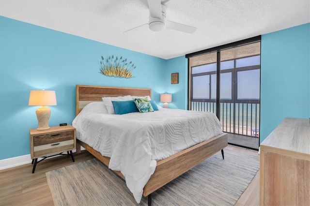 15400 Gulf Blvd Unit 202, Madeira Beach, FL 33708 - bedroom featuring wood finished floors, access to exterior, baseboards, a textured ceiling, and a ceiling fan