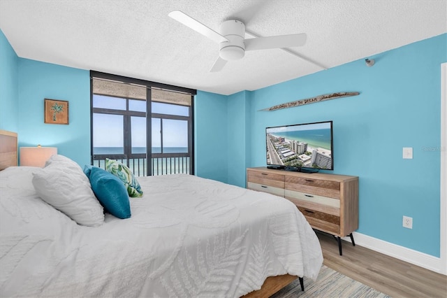 15400 Gulf Blvd Unit 202, Madeira Beach, FL 33708 - bedroom with ceiling fan, floor to ceiling windows, a textured ceiling, wood finished floors, and baseboards