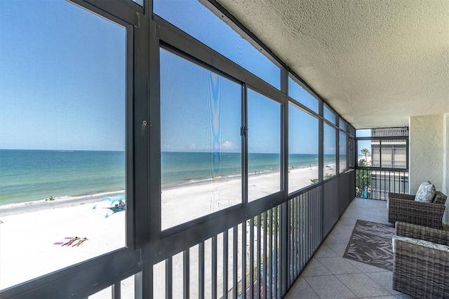 15400 Gulf Blvd Unit 202, Madeira Beach, FL 33708 - sunroom featuring a beach view, a water view, and a textured ceiling