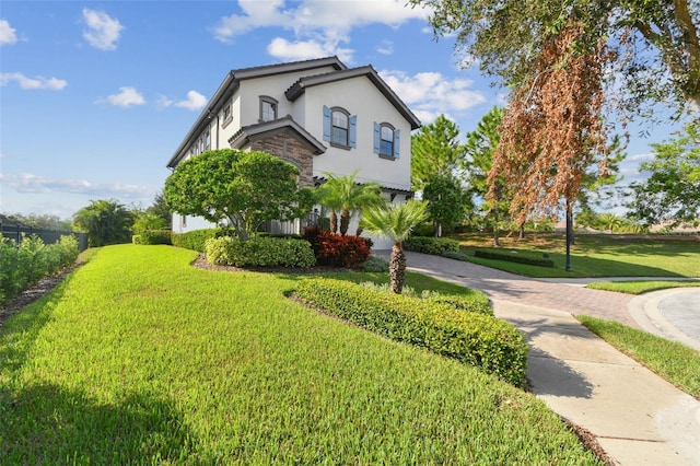 view of side of home with driveway, a lawn, a garage, stone siding, and stucco siding