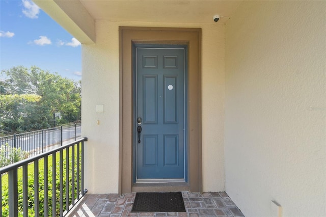 property entrance with stucco siding and a balcony