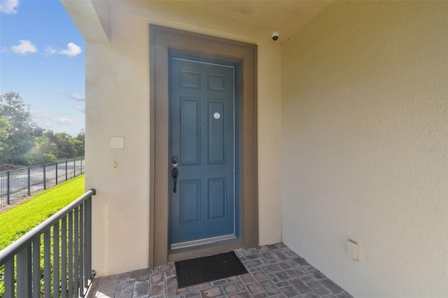 entrance to property featuring a balcony and stucco siding