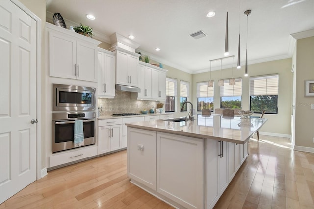kitchen with crown molding, a sink, white cabinetry, and stainless steel appliances
