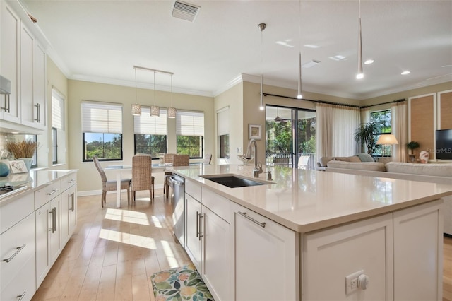 kitchen with white cabinets, a sink, light countertops, visible vents, and ornamental molding