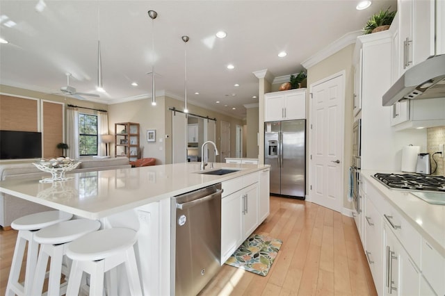 kitchen with crown molding, appliances with stainless steel finishes, a sink, a ceiling fan, and open floor plan