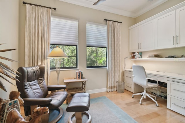 home office with built in desk, baseboards, ornamental molding, and light wood-style flooring