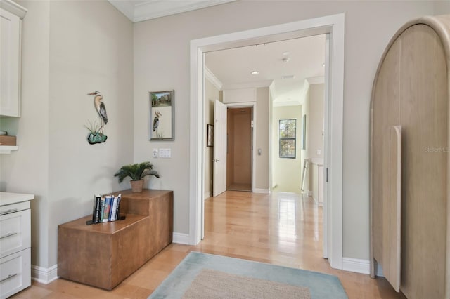 hall with baseboards, ornamental molding, and light wood finished floors