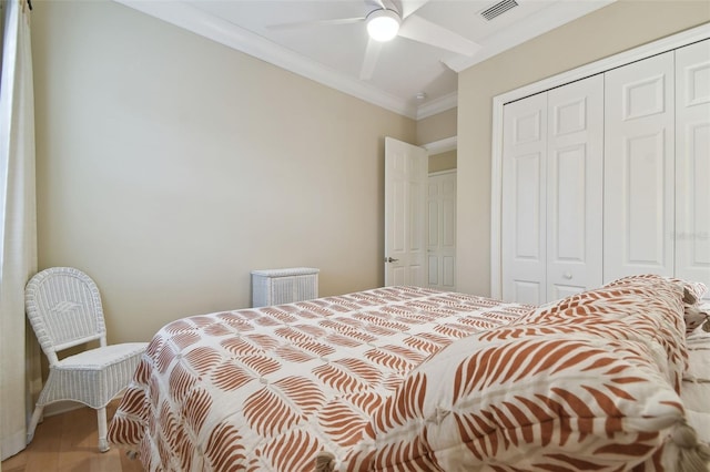 bedroom with ceiling fan, visible vents, crown molding, wood finished floors, and a closet