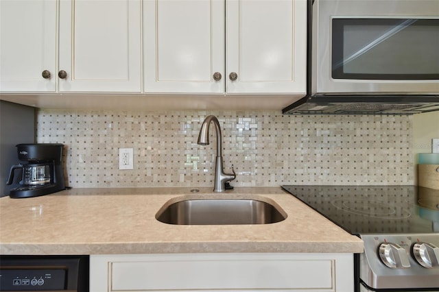 kitchen featuring electric range oven, a sink, light countertops, white cabinets, and stainless steel microwave