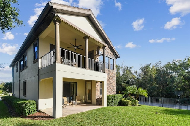 back of house featuring a patio, stucco siding, stone siding, and a balcony
