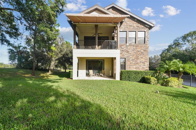 back of property featuring a ceiling fan, a yard, a balcony, and stone siding