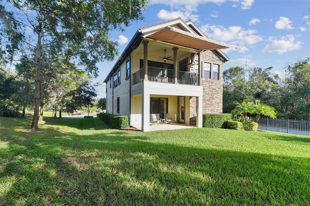 back of property featuring a lawn, a patio, a ceiling fan, and a balcony