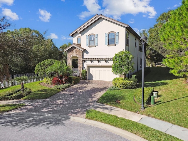 mediterranean / spanish house with decorative driveway, fence, a front lawn, and a garage