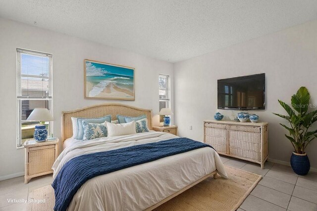 bedroom featuring a textured ceiling, light tile patterned floors, and baseboards