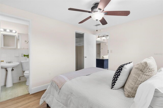 8184 Rose Ter, Seminole, FL 33777 - bedroom with light wood-type flooring, tile walls, visible vents, a closet, and ensuite bath