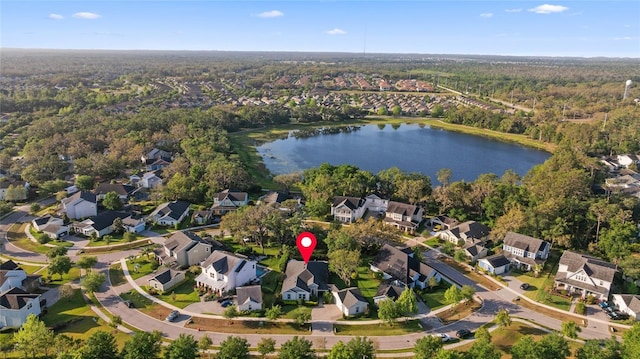 view of property location featuring nearby suburban area, a large body of water, and a heavily wooded area