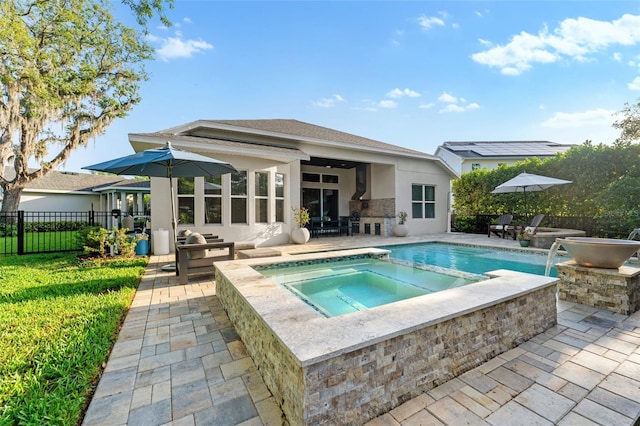 back of property featuring an in-ground hot tub, stucco siding, a patio area, and stone siding