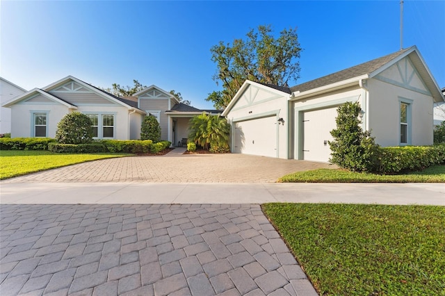 view of front of house with stucco siding, decorative driveway, an attached garage, and a front yard