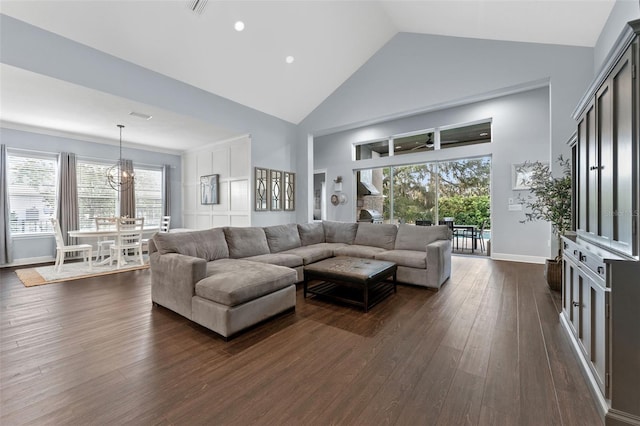 living area featuring dark wood-style flooring, high vaulted ceiling, healthy amount of natural light, a chandelier, and baseboards