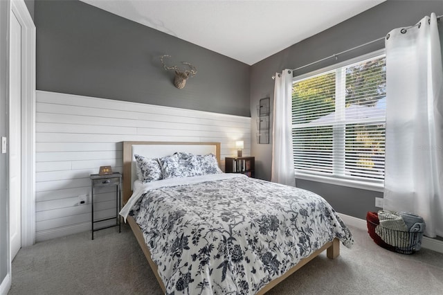 bedroom with carpet floors, baseboards, and wooden walls