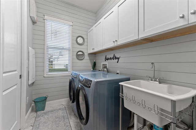 washroom featuring washer and clothes dryer, wood walls, cabinet space, baseboards, and marble look tiles