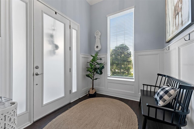 doorway featuring a decorative wall, wainscoting, and dark wood finished floors