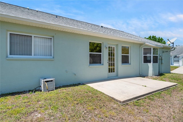 back of house with a yard, a patio, roof with shingles, and stucco siding
