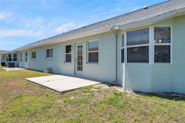 rear view of house featuring a lawn, a patio, central AC unit, and stucco siding
