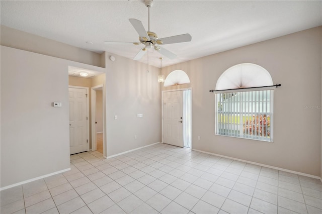 empty room featuring baseboards, a ceiling fan, and light tile patterned floors