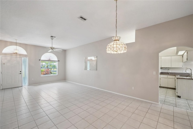 unfurnished dining area with visible vents, ceiling fan, arched walkways, a sink, and light tile patterned floors
