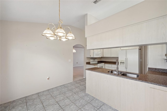 kitchen featuring arched walkways, light tile patterned floors, a peninsula, a notable chandelier, and white appliances