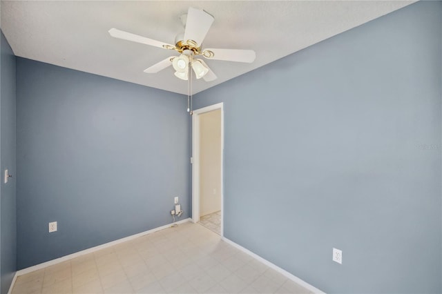 spare room with a ceiling fan and baseboards