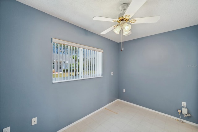 empty room with baseboards, a ceiling fan, and a textured ceiling