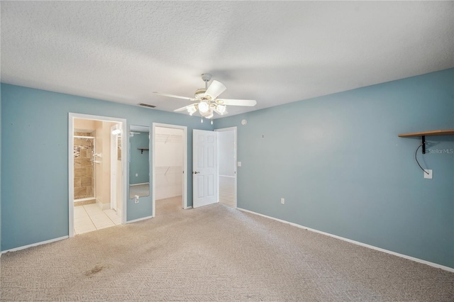 unfurnished bedroom featuring connected bathroom, carpet floors, baseboards, a spacious closet, and visible vents