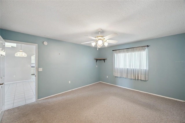 carpeted empty room with baseboards, a ceiling fan, and a textured ceiling