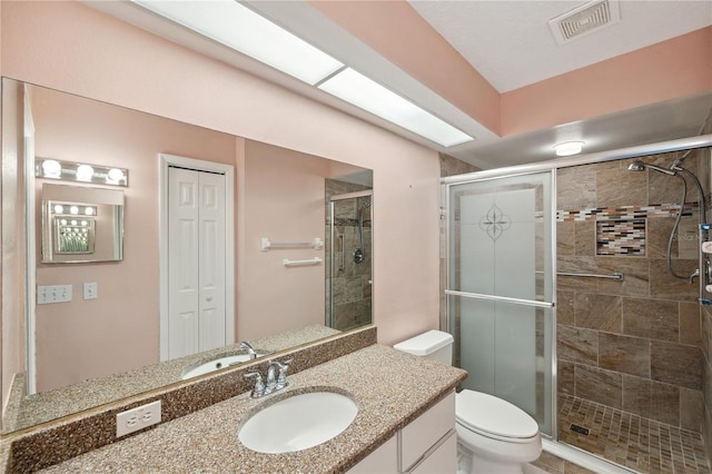 full bathroom featuring vanity, toilet, visible vents, and a stall shower