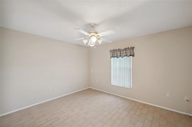 empty room with baseboards, ceiling fan, and light wood-type flooring