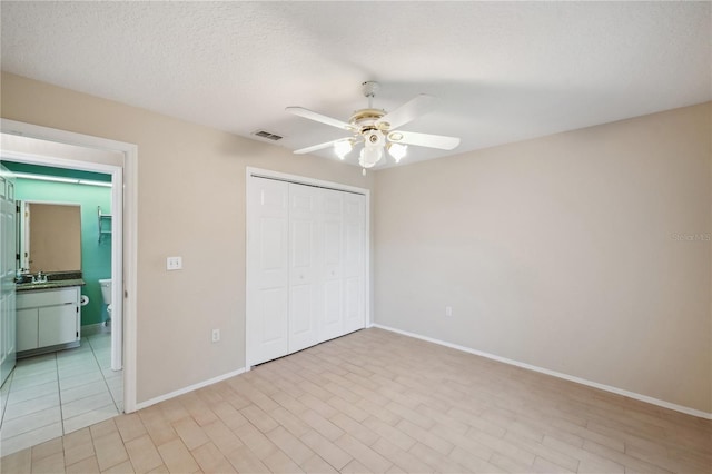 unfurnished bedroom with baseboards, visible vents, a sink, and a closet