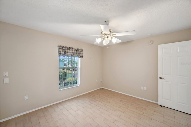 empty room featuring a textured ceiling, ceiling fan, and baseboards