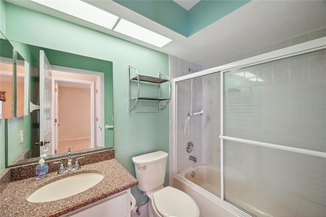 bathroom with bath / shower combo with glass door, vanity, and toilet