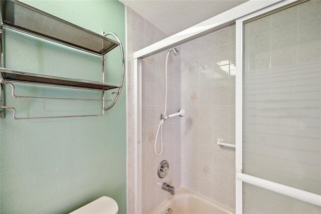 full bathroom with bath / shower combo with glass door and toilet