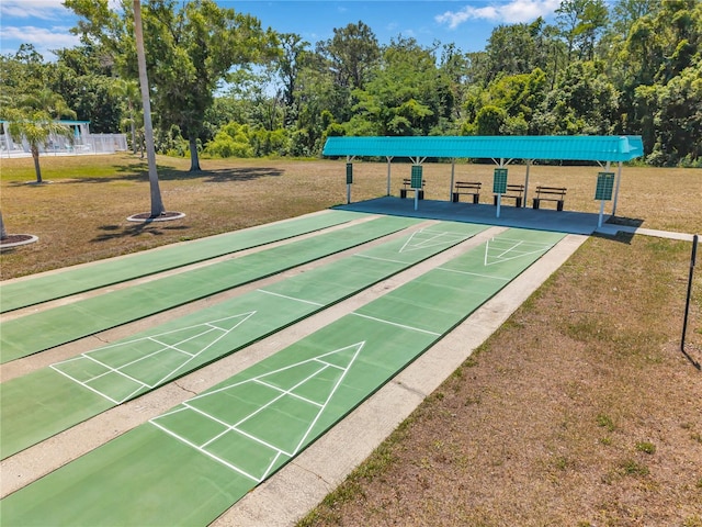 view of property's community featuring a yard and shuffleboard