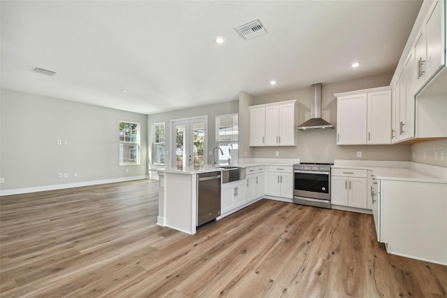 1522 W Arch St, Tampa, FL 33607 - kitchen featuring visible vents, a peninsula, wall chimney exhaust hood, a sink, and appliances with stainless steel finishes